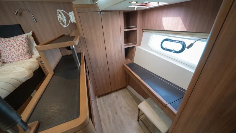 Slide: The Image of Guest Cabin with Desk Area This guest cabin on the 2021 Aquila 44 CAT features a cozy sleeping area and a functional desk space. The wood finishes provide a warm ambiance, complemented by natural light from the window. Ample storage options and a comfortable layout make this an inv - 7413968