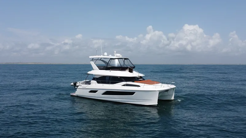 Slide: The Image of Side View of Aquila 44 CAT The Aquila 44 CAT 'Hey Beautiful' gracefully cuts through the water, showcasing its sleek and modern design. This 2021 model features a spacious flybridge and elegant lines that complement its robust, twin-hull structure. The expansive windows provide pan - 7414002
