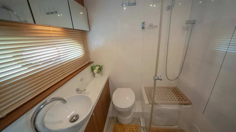 Slide: The Image of Modern Ensuite Bathroom This sleek ensuite bathroom on the Aquila 44 CAT features a stylish vessel sink and contemporary fixtures. The space is brightened by natural light filtering through wooden blinds, complementing the elegant wood finishes. A spacious glass-enclosed shower - 7413958