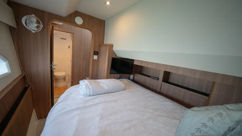Slide: The Image of Guest Stateroom with Ensuite Access This cozy guest stateroom on the Aquila 44 CAT features a comfortable double bed adorned with soft linens, creating a welcoming retreat. The wood finishes add warmth to the space, while the integrated shelving provides practical storage. An ensuite bathro - 7413957