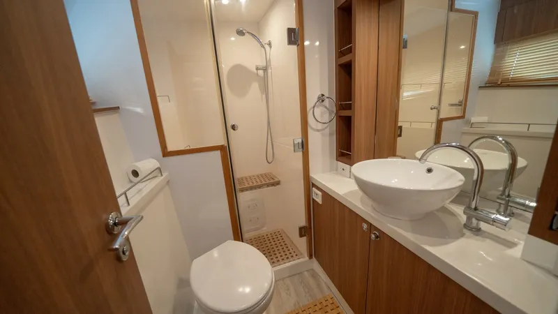 Slide: The Image of Modern Ensuite Bathroom with Shower This elegant ensuite bathroom on the Aquila 44 CAT features a sleek walk-in shower with a glass door, providing a spacious feel. The contemporary design includes a stylish vessel sink atop a solid surface countertop, complemented by warm wood cabinetry fo - 7413972