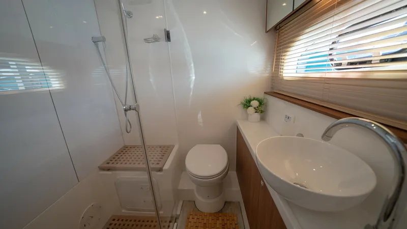 Slide: The Image of Elegant Ensuite Bathroom This stylish ensuite bathroom on the Aquila 44 CAT features a modern design with a spacious glass-enclosed shower and sleek fixtures. The room is accentuated by a contemporary vessel sink and ample natural light streaming through the window blinds. Rich w - 7413966