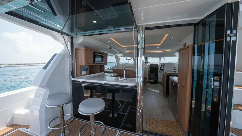 Slide: The Image of Aft Deck and Interior Salon View This image showcases the seamless transition from the aft deck to the interior salon of the 2021 Aquila 44 CAT. The spacious deck features elegant bar seating, ideal for entertaining while enjoying ocean views. Inside, the modern salon is equipped with sl - 7413973
