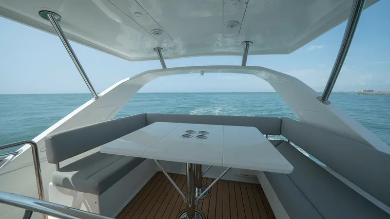 Slide: The Image of Flybridge Seating Area with Ocean View The flybridge of the Aquila 44 CAT offers a spacious seating area with plush bench seating surrounding a sleek, modern table. The area is sheltered by a stylish hardtop, providing shade while maintaining an open-air atmosphere, perfect for entertaining or - 7413981