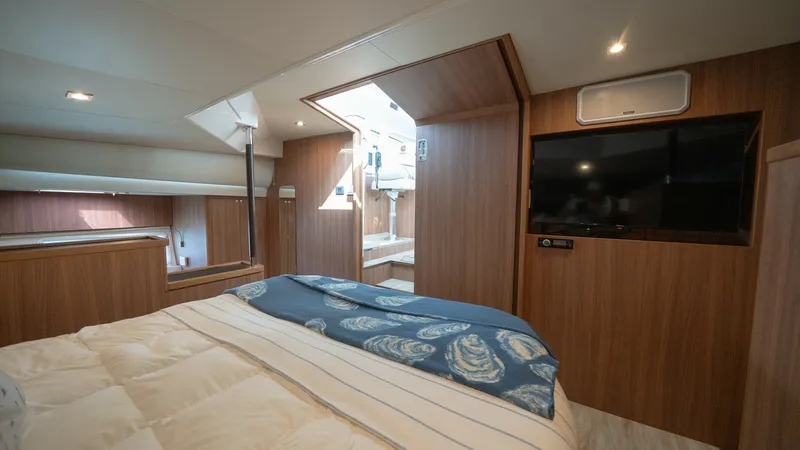 Slide: The Image of Master Stateroom with Ensuite Access The master stateroom of the 2021 Aquila 44 CAT features a spacious layout with elegant wood finishes. A large, comfortable bed is complemented by natural light streaming in from the overhead skylight. The room also includes a flat-screen TV and seamless a - 7413971