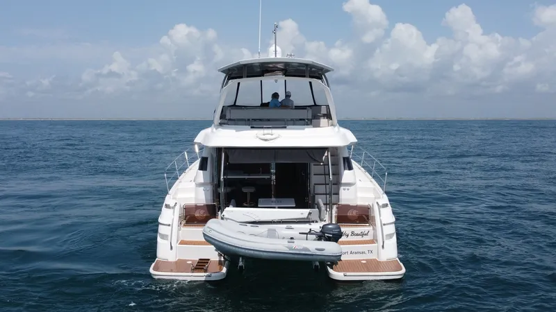 Slide: The Image of Aft View with Tender The aft view of the 2021 Aquila 44 CAT showcases a spacious swim platform equipped with a tender, ideal for easy water access. The elegant design features integrated steps leading to the main deck, enhancing functionality and style. The sleek lines and am - 7414036