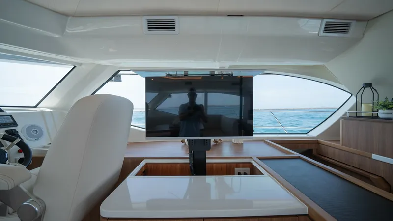 Slide: The Image of Helm Station with Entertainment System This helm station on the 2021 Aquila 44 CAT features a sleek, modern design with a large flat-screen monitor prominently displayed. The blend of wood finishes and leather seating offers both luxury and comfort, while expansive windows provide panoramic oc - 7413979