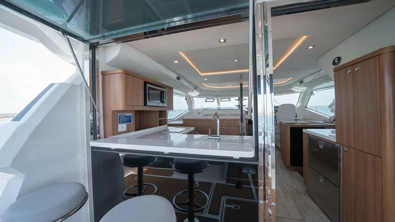 Slide: The Image of Spacious Galley and Salon Area This image showcases the modern galley and salon of the 2021 Aquila 44 CAT. The galley features sleek countertops, a built-in microwave, and ample storage, seamlessly transitioning into the salon area with elegant overhead lighting. The open layout and la - 7413974