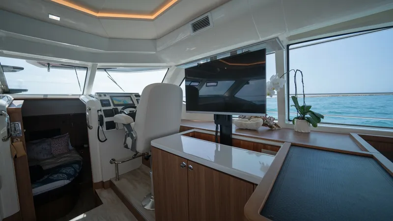 Slide: The Image of Main Helm and Interior Lounge Area The helm of the 2021 Aquila 44 CAT showcases a modern, ergonomic captain's chair with a comprehensive control panel, ensuring easy navigation. Adjacent to the helm, the interior lounge features a sleek entertainment system and expansive windows offering p - 7413978