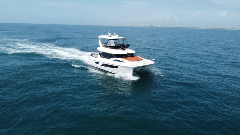 Slide: The Image of Aquila 44 CAT Cruising Aerial View The Aquila 44 CAT, 'Hey Beautiful', is captured cruising gracefully across open waters. This 2021 model showcases a sleek and modern design with a spacious flybridge and sunpad on the foredeck, perfect for relaxation and entertainment. The twin-hull confi - 7414015