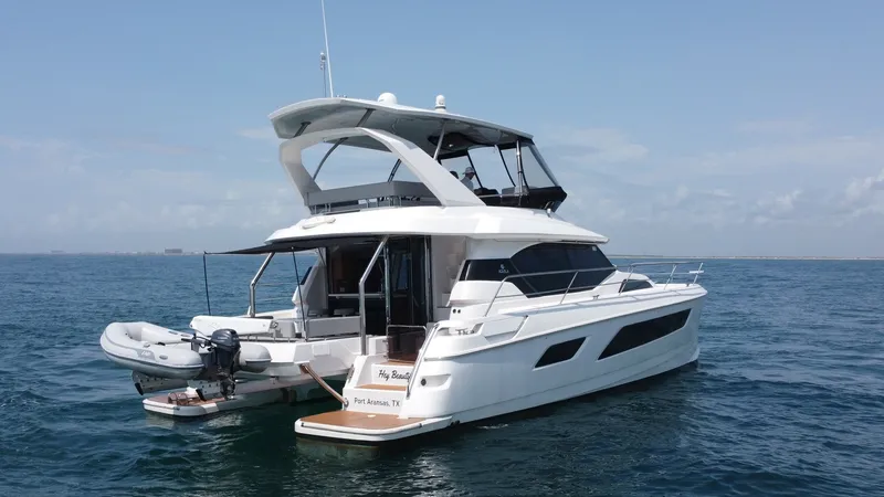 Slide: The Image of Aquila 44 CAT Aft View with Dinghy This image showcases the elegant aft view of the 2021 Aquila 44 CAT, highlighting its sleek lines and spacious upper deck. The vessel features a hydraulic swim platform with an attached dinghy, perfect for easy water access. The flybridge offers ample sea - 7414038
