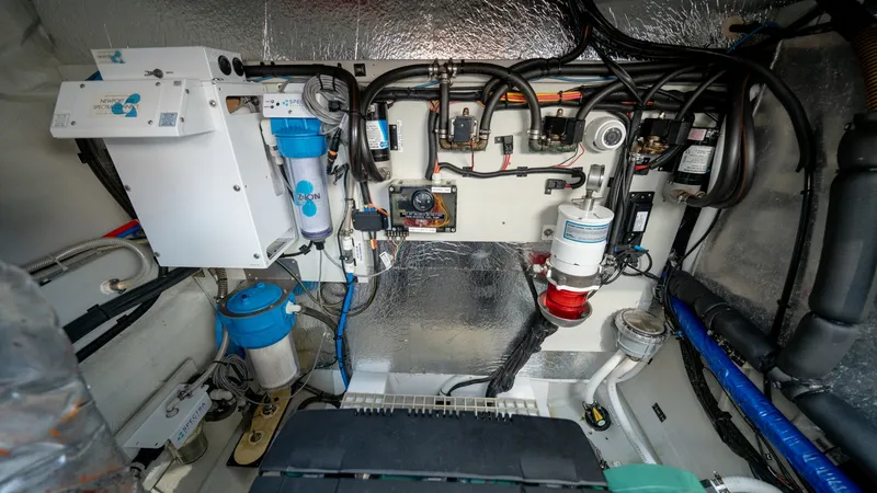 Slide: The Image of Engine Room and Systems Overview The image showcases the well-organized engine room of the Aquila 44 CAT, featuring advanced mechanical systems. Visible are the neatly arranged wiring and piping, along with essential components such as filters and pumps. The reflective insulation and pro - 7413995
