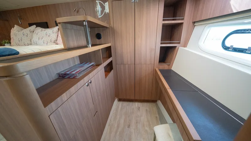 Slide: The Image of Portside Stateroom with Desk Area This elegant portside stateroom on the 2021 Aquila 44 CAT features warm wood finishes and ample storage. A built-in desk area with a comfortable stool offers a functional workspace, enhanced by natural light from the side window. The cabin design combines - 7413967