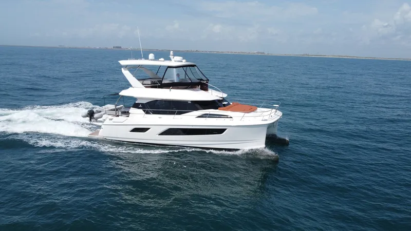 Slide: The Image of Aquila 44 CAT Cruising Side View The 2021 Aquila 44 CAT, 'Hey Beautiful,' is showcased cruising gracefully on open waters. This side view highlights the sleek, modern lines of the catamaran, with expansive windows offering panoramic views. The spacious flybridge and forward lounging area - 7414005