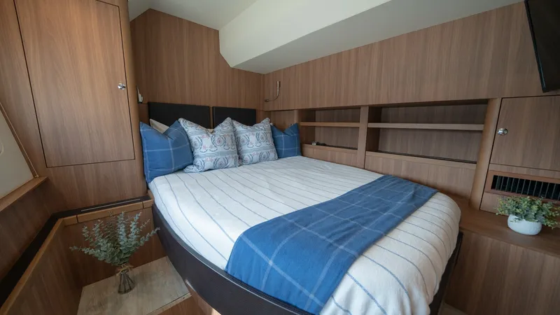 Slide: The Image of Cozy Guest Stateroom The guest stateroom on the Aquila 44 CAT features a plush double bed adorned with elegant blue and white bedding, creating a welcoming retreat. Warm wood finishes enhance the cabinetry and walls, providing ample storage and a sophisticated aesthetic. Natu - 7413962