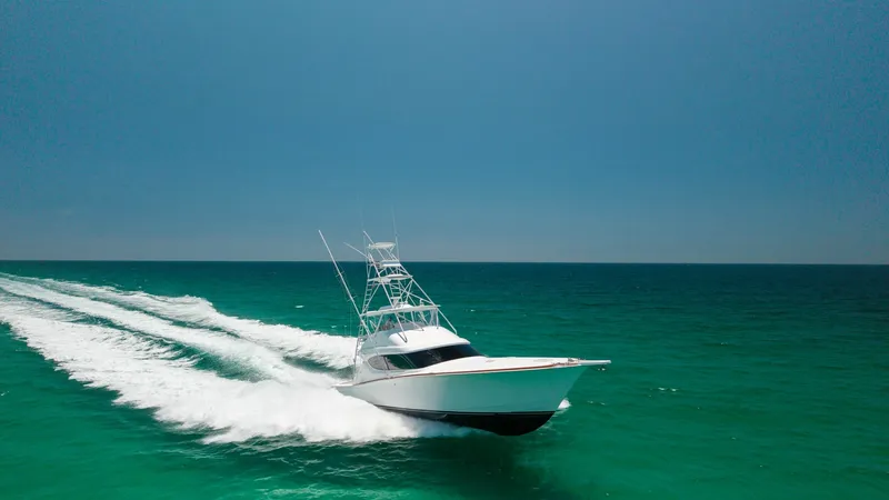 Slide: The Image of Hatteras 60 GT at Speed The 2010 Hatteras 60 GT, 'Knot Diggin', powers through open waters with impressive speed and agility. Its sleek, aerodynamic design is perfectly captured against the clear blue sea, showcasing the yacht's superior craftsmanship. The elevated flybridge off - 7396006