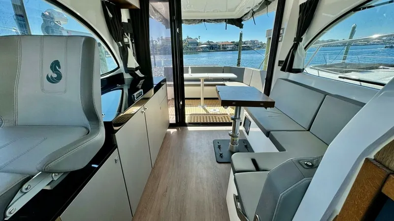 Slide: The Image of Interior Salon with Helm and Seating The interior salon of the 2022 Beneteau Antares 11 features a modern helm station with a sleek, ergonomic design. Comfortable seating runs along one side, paired with a versatile table, perfect for dining or socializing. Large windows and sliding glass do - 7403677