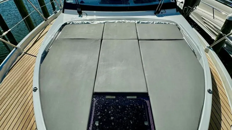 Slide: The Image of Spacious Foredeck Sunpad Area This image showcases the expansive foredeck sunpad on the 2022 Beneteau Antares 11. The plush, cushioned area offers ample space for relaxation and sunbathing, surrounded by sleek stainless steel railings for safety. The teak decking adds a touch of elega - 7403696