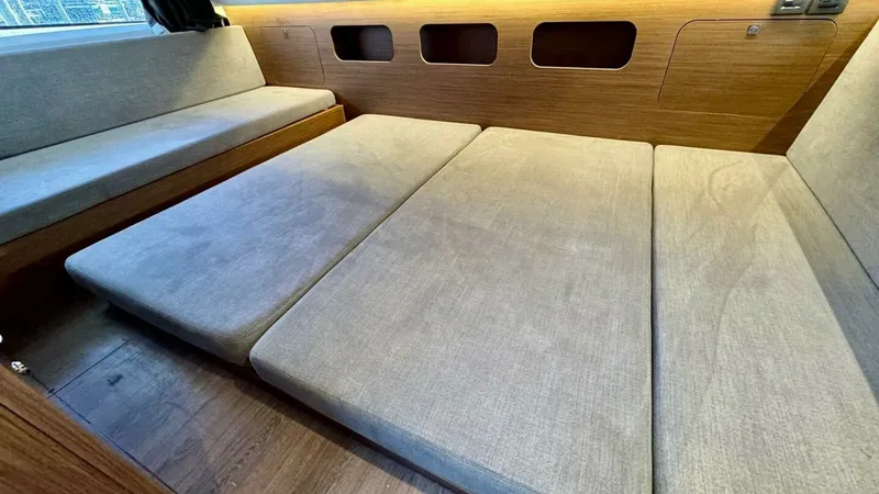 Slide: The Image of Convertible Cabin Lounge Area This inviting cabin space on the 2022 Beneteau Antares 11 showcases a versatile layout with plush, convertible seating that transforms into a comfortable sleeping area. The warm wood paneling and ambient lighting create a cozy atmosphere, making it perfec - 7403684