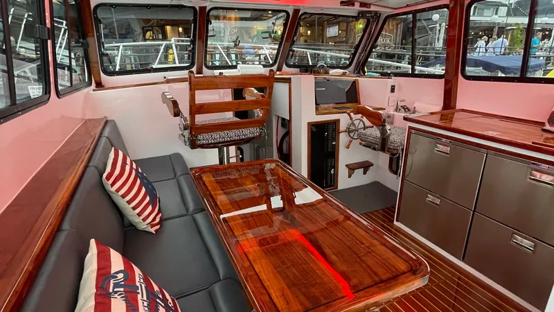 Slide: The Image of Stylish Interior Helm and Seating Area The interior of the BEAR FLAG III showcases a sophisticated helm station with a captain's chair and extensive glazing for panoramic views. The seating area features plush cushions and a polished wooden table, complemented by nautical-themed decor. Stainle - 7398001