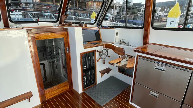 Slide: The Image of Flybridge Helm with Teak Accents The helm of the 2019 Donelle 36 Flybridge Sportfish features elegant teak finishes, providing a classic maritime aesthetic. Large windows offer expansive views and natural light, enhancing the navigation experience. The helm is equipped with modern contro - 7397990
