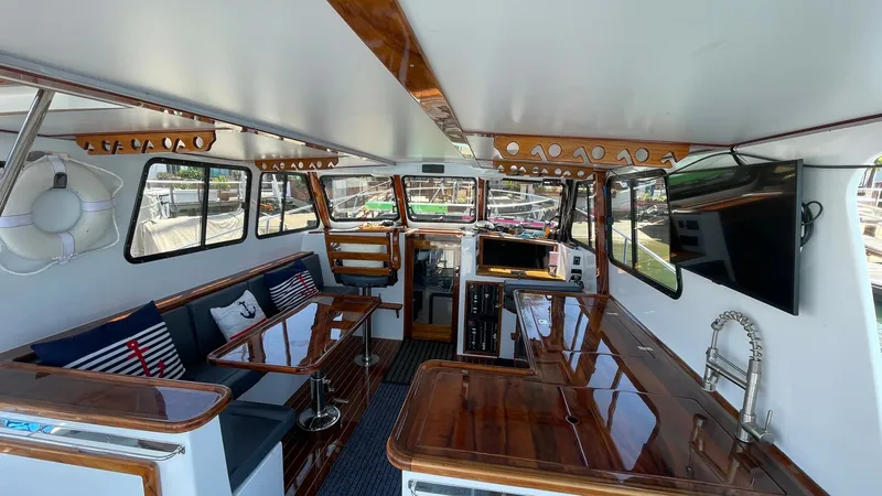 Slide: The Image of Spacious Flybridge Interior Lounge Area This inviting flybridge interior offers ample seating with plush cushions and nautical-themed decor, perfect for entertaining. The polished wood finishes add a touch of elegance, complemented by modern amenities like a wall-mounted TV for leisure. Large w - 7397995