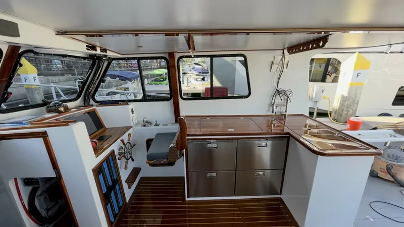 Slide: The Image of Helm and Galley Area This image showcases the helm and galley area of the 2019 Donelle 36 Flybridge Sportfish. The helm features a classic wooden steering wheel and modern navigation equipment, offering both style and functionality. Adjacent is the galley, equipped with stain - 7397997