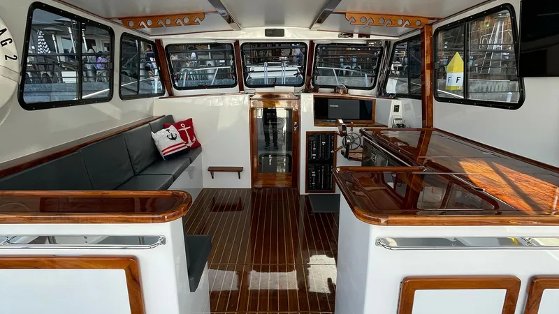 Slide: The Image of Spacious Flybridge Interior The flybridge interior of the BEAR FLAG III showcases a luxurious and functional layout with rich wood finishes and expansive windows for panoramic views. The seating area is elegantly designed with plush cushions, providing comfort and style. A modern he - 7397996