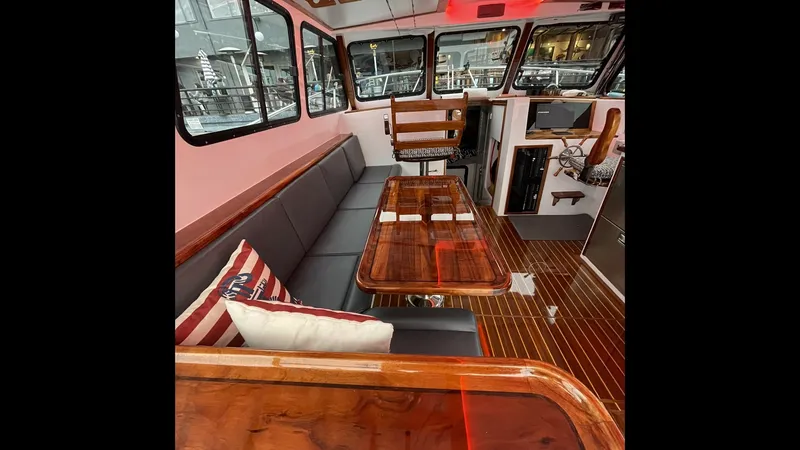 Slide: The Image of Main Salon with Seating and Helm The main salon of the 2019 Donelle 36 Flybridge Sportfish features a sleek, contemporary design with ample seating. A plush L-shaped sofa offers comfort, complemented by a polished wooden table for dining or socializing. The helm station is neatly integra - 7398002