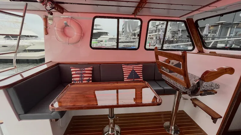 Slide: The Image of Flybridge Sportfish Interior Seating Area This inviting interior seating area on the 2019 Donelle 36 Flybridge Sportfish features a polished wooden table surrounded by plush, cushioned benches. Nautical-themed pillows add a touch of charm, while large windows provide ample natural light and stunn - 7398000