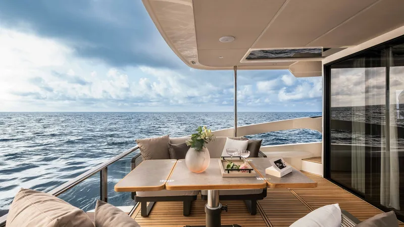 Slide: The Image of Aft Deck with Expansive Ocean View The aft deck of the 2027 Absolute Navetta 50 offers a luxurious outdoor space with stunning ocean views. It features a stylish dining area with a sleek wooden table, surrounded by plush seating for ultimate comfort. The elegant overhead canopy provides sh - 7514464