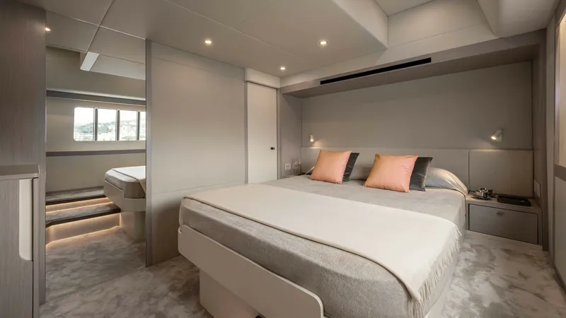 Slide: The Image of Master Stateroom of Navetta 50 The master stateroom of the 2027 Navetta 50 offers a spacious retreat with a luxurious queen-sized bed, accented by plush cushions. Soft ambient lighting and large windows create a bright, inviting atmosphere, while high-quality finishes and modern design - 7514474