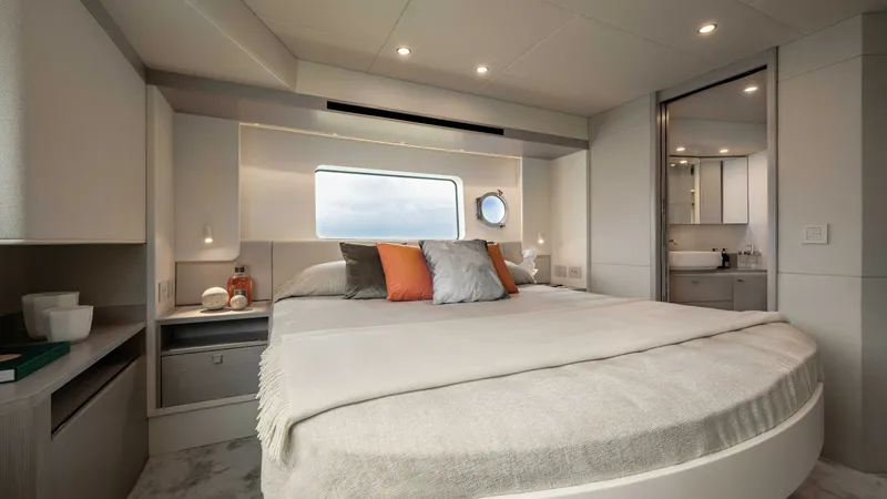 Slide: The Image of Master Stateroom with En-Suite This luxurious master stateroom on the 2027 Absolute Navetta 50 offers a spacious and serene retreat with a plush double bed and elegant bedding. Large windows and a porthole provide abundant natural light and stunning sea views. The en-suite bathroom fea - 7514471
