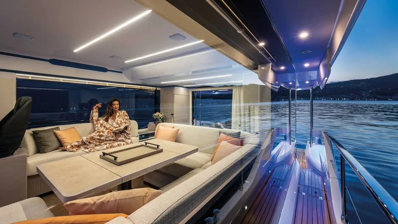 Slide: The Image of Elegant Salon with Panoramic Views The salon of the 2027 Absolute Navetta 50 showcases a luxurious seating area with plush cushions and a sophisticated table, perfect for entertaining or relaxing. Floor-to-ceiling windows offer breathtaking panoramic views, seamlessly blending indoor comfo - 7514478