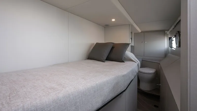 Slide: The Image of Guest Cabin with Ensuite The guest cabin aboard the 2027 Absolute Navetta 50 offers a cozy and modern retreat. It features a comfortable single bed with plush bedding and stylish accents. The cabin includes an ensuite bathroom, providing privacy and convenience for guests. - 7514477
