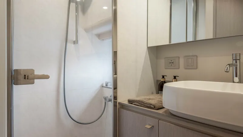 Slide: The Image of Elegant Bathroom with Modern Amenities The bathroom of the 2027 Absolute Navetta 50 showcases contemporary design with a sleek glass-enclosed shower and a stylish vessel sink. The use of high-quality materials and subtle lighting enhances the luxurious atmosphere. Ample storage and elegant fix - 7514475