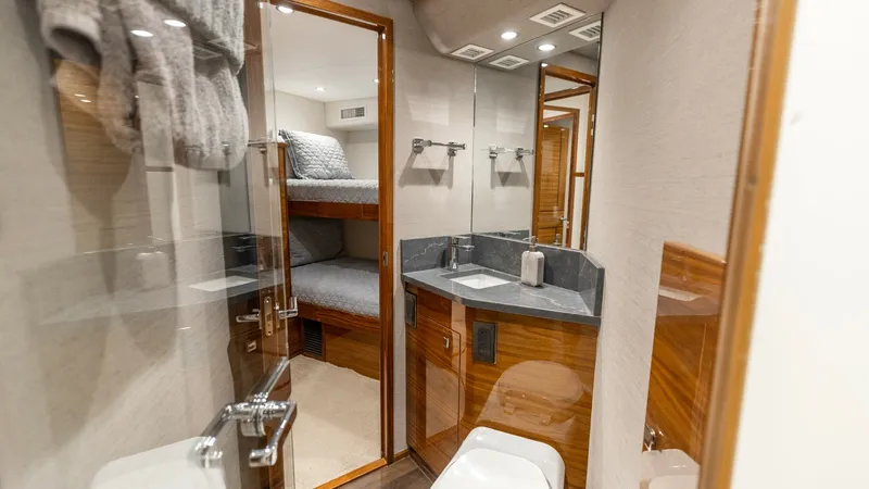 Slide: The Image of Guest Head with Bunk Access This elegant guest head on the Viking 74 Convertible features high-gloss wood finishes and modern fixtures. The well-appointed vanity boasts a sleek countertop, while ample lighting enhances the space's functionality. A door leads directly to a cozy bunk - 7531180
