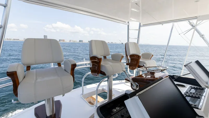 Slide: The Image of Flybridge Helm with Seating The flybridge helm of the 2025 Viking 74 Convertible features plush captain's chairs with sleek wooden accents, offering comfort and style. The state-of-the-art control panel provides advanced navigation technology, ensuring a seamless piloting experience - 7531197