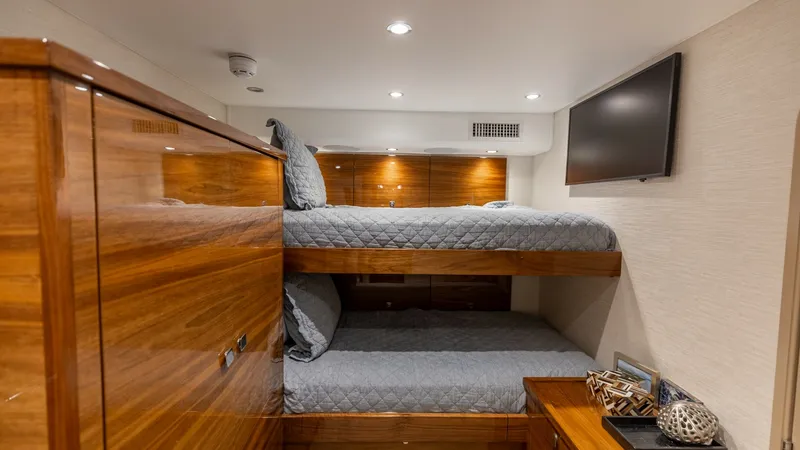 Slide: The Image of Guest Stateroom with Bunk Beds This inviting guest stateroom on the 2025 Viking 74 Convertible features comfortable bunk beds, ideal for accommodating guests. The room is elegantly appointed with rich wood finishes and modern amenities, including a flat-screen TV mounted on the wall fo - 7531182