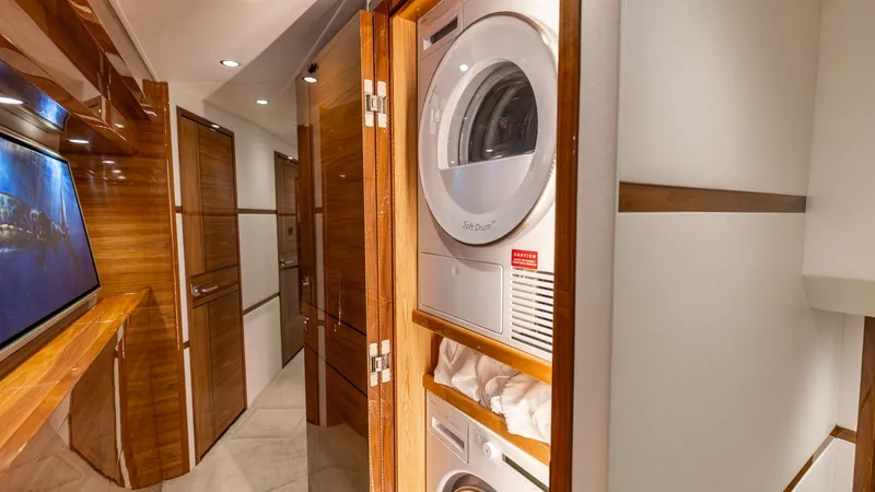 Slide: The Image of Hallway with Laundry Station This Viking 74 Convertible features a sleek hallway with warm wooden finishes and recessed lighting. The built-in laundry station, equipped with a modern washer and dryer, is neatly integrated behind wooden doors, ensuring functionality without compromisi - 7531176