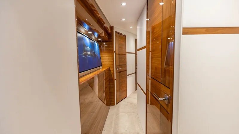 Slide: The Image of Elegant Interior Hallway This sophisticated hallway on the 2025 Viking 74 Convertible features high-gloss wood finishes and recessed lighting, creating a warm and inviting ambiance. The plush carpeting adds a touch of luxury underfoot, while sleek cabinetry provides ample storage - 7531177
