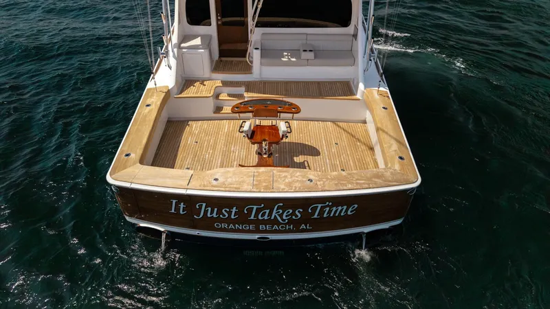 Slide: The Image of Aft Deck and Transom View The aft deck of the 2025 Viking 74 Convertible 'It Just Takes Time' showcases a spacious fishing area with a high-quality teak finish. A central fighting chair is prominently positioned, ideal for sport fishing enthusiasts. The open layout and access to t - 7531207
