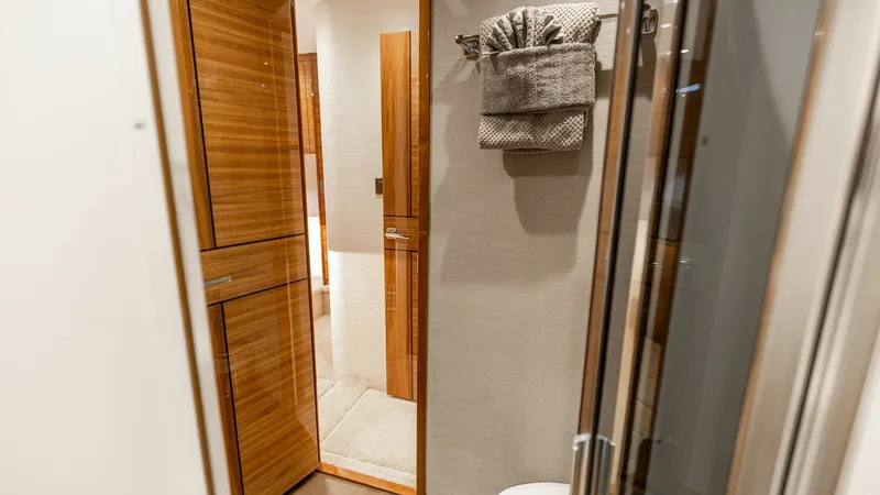 Slide: The Image of Luxurious Ensuite Bathroom View This image showcases a beautifully designed ensuite bathroom aboard the 2025 Viking 74 Convertible. Featuring high-gloss wood cabinetry and modern fixtures, the space exudes sophistication. The soft lighting and elegant finishes contribute to a sense of l - 7531174