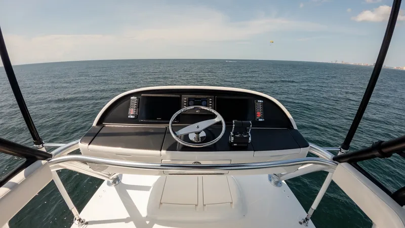 Slide: The Image of Flybridge Helm Station Overview The helm station on the flybridge of the 2025 Viking 74 Convertible offers a commanding view of the open sea, complemented by state-of-the-art navigation and control systems. The sleek design features ergonomic seating and a clean console layout, ensuring - 7531203