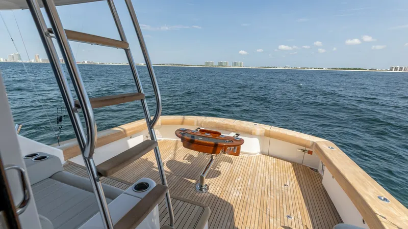Slide: The Image of Spacious Aft Deck with Ladder Access This inviting aft deck on the 2025 Viking 74 Convertible features elegant teak flooring and a well-crafted fighting chair, ideal for fishing enthusiasts. The stainless steel ladder provides easy access to the upper decks, while the built-in seating offers - 7531196