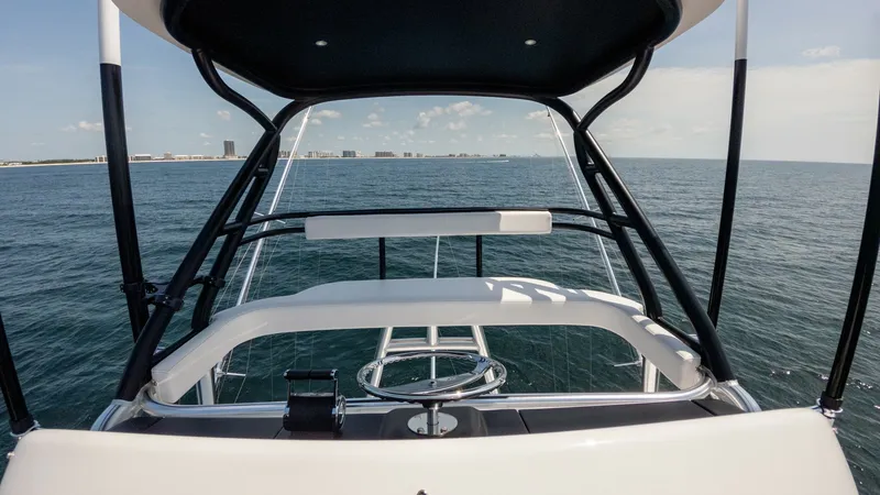 Slide: The Image of Flybridge Helm Station View This image showcases the flybridge helm station of the 2025 Viking 74 Convertible, 'It Just Takes Time.' The sleek design features a modern steering wheel and an intuitive console layout, offering commanding views of the open sea. The overhead canopy prov - 7531204