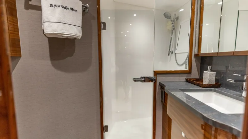 Slide: The Image of Luxurious Ensuite Bathroom This elegant ensuite bathroom aboard the 2025 Viking 74 Convertible features a sleek glass-enclosed shower and a modern vanity with a polished countertop. The rich wood finishes and high-quality fixtures enhance the space, providing both functionality and - 7531170