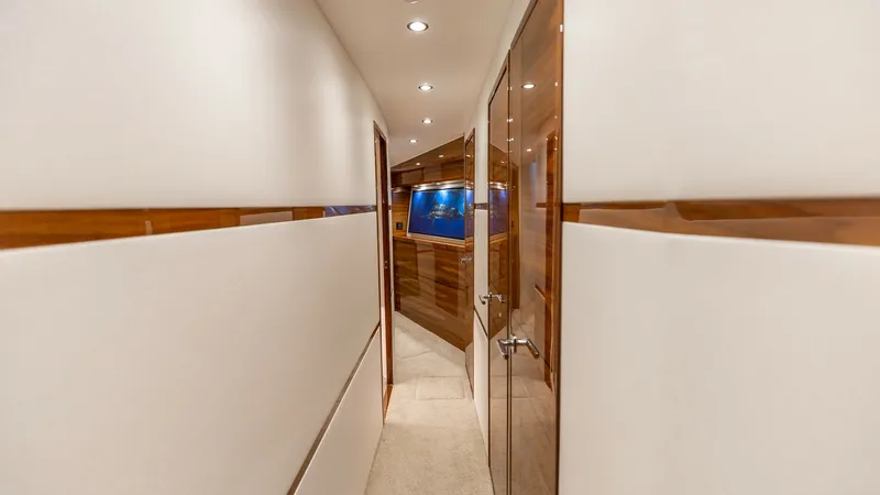 Slide: The Image of Elegant Interior Hallway View This image showcases the sleek and contemporary interior hallway of the 2025 Viking 74 Convertible. The passageway features high-gloss wood accents and soft, ambient lighting that enhances the luxurious ambiance. The polished finishes and stylish design e - 7531175