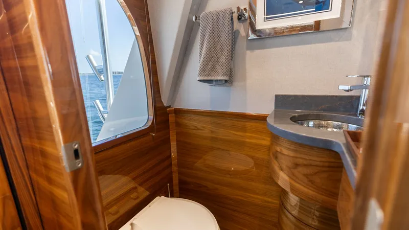 Slide: The Image of Elegant En-Suite Head This sophisticated en-suite head on the 2025 Viking 74 Convertible features sleek wooden cabinetry and contemporary fixtures. The room is well-appointed with a modern sink and a stylish chrome faucet, complemented by natural light streaming through the wi - 7531165