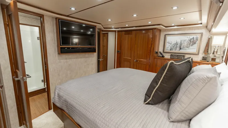 Slide: The Image of Luxurious Master Stateroom This master stateroom aboard the 2018 Viking 72 Convertible features a plush queen-sized bed with elegant bedding and ample storage space. The room is beautifully appointed with warm wood accents and recessed lighting, creating a cozy yet sophisticated at - 7460584